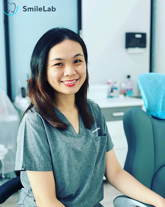 A SmileLab dentist in the clinic, in grey scrubs, with the dental chair and clinic interior in the background.